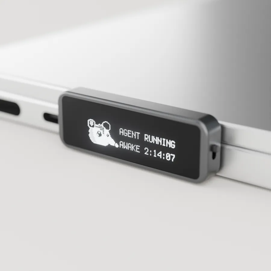 Render: the Possum key along the side of a closed MacBook. Its screen shows a pixel possum and reads Agent running, awake 2:14:07.