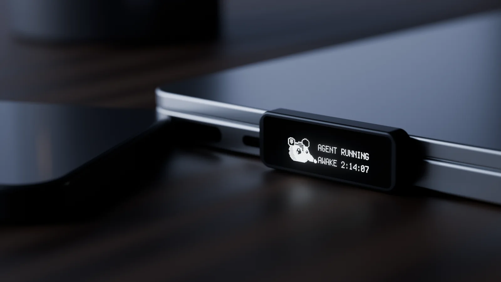 Render: a closed MacBook at night with the Possum key along its side. The key's small screen glows with a pixel possum and reads Agent running, awake 2:14:07.